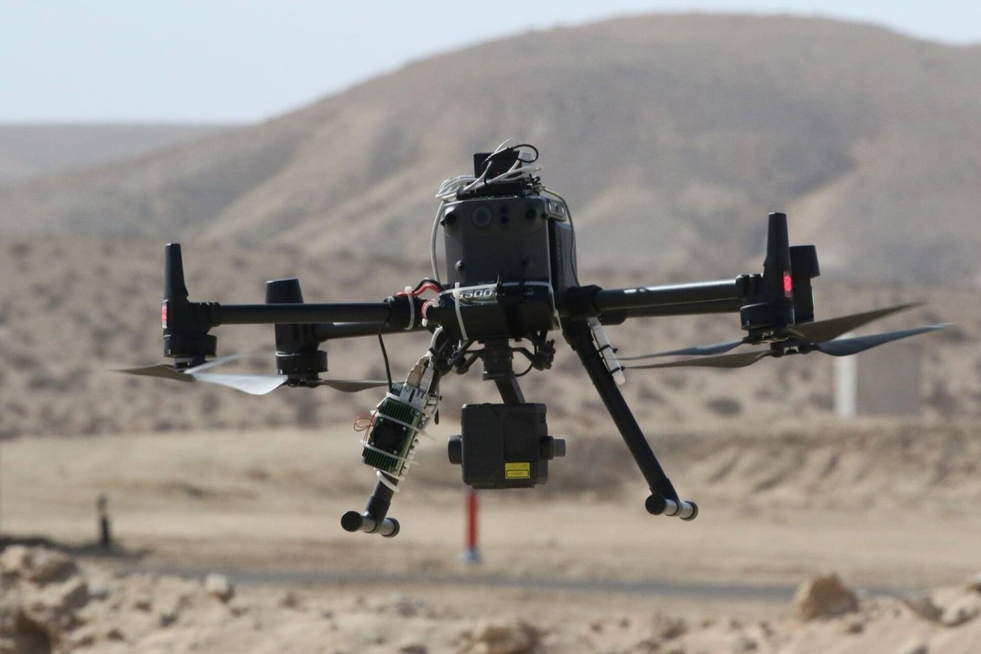 Drone professionnel en vol stationnaire au-dessus d'un terrain d'essai désertique