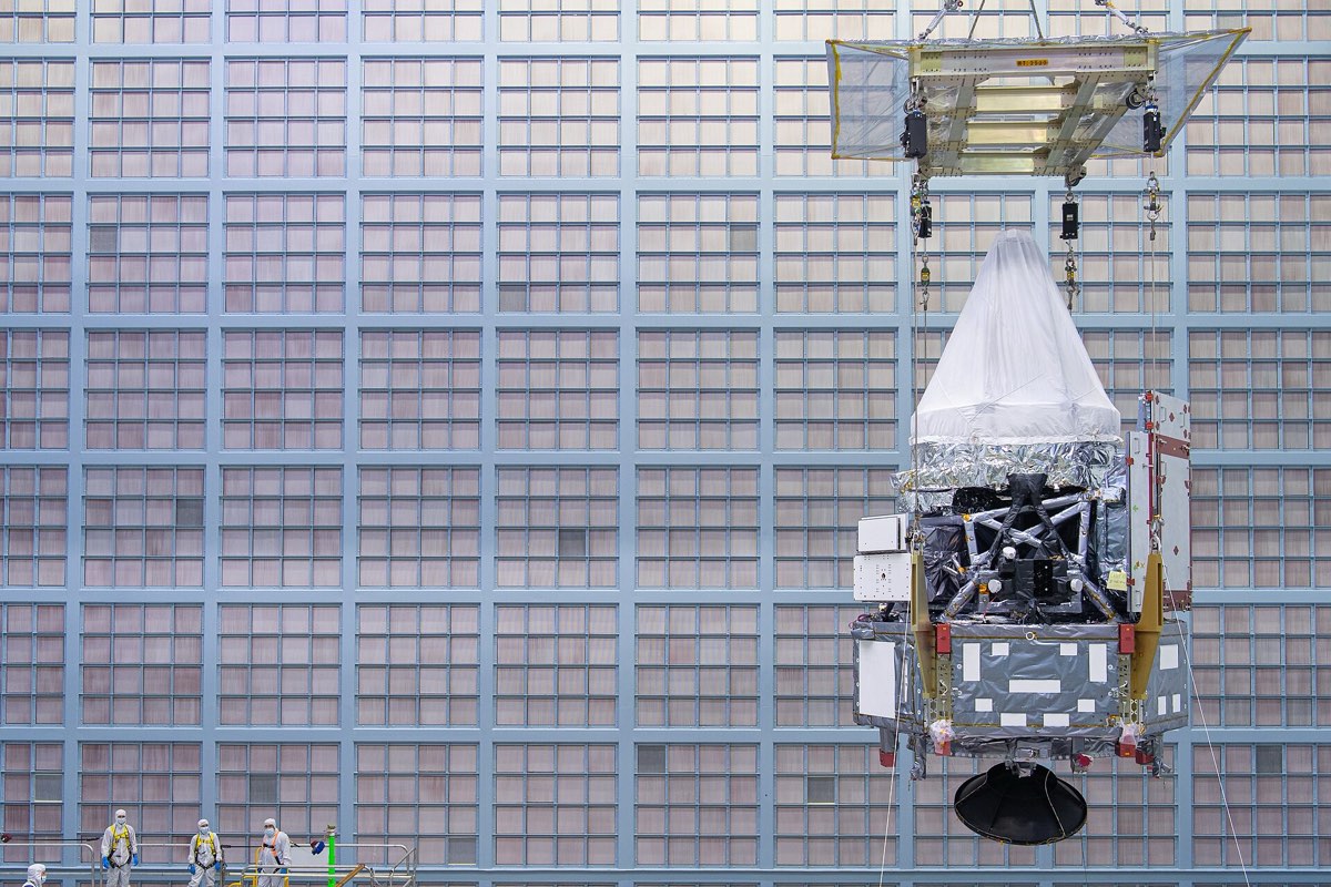 Un module de satellite soulevé au pont roulant dans une salle blanche